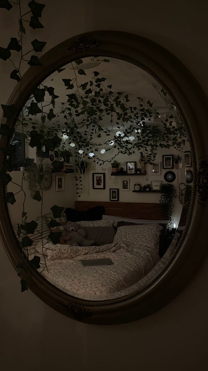 there is a mirror that has some plants in the reflection and lights on the wall behind it