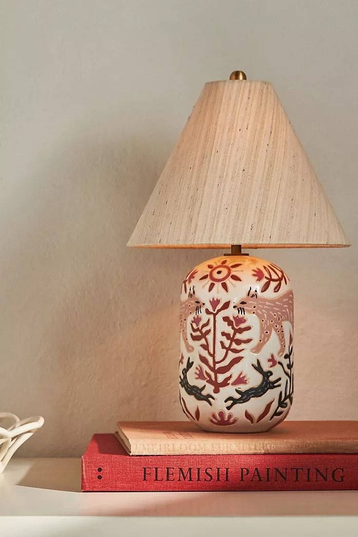 a lamp sitting on top of a book next to a lamp with a bird design