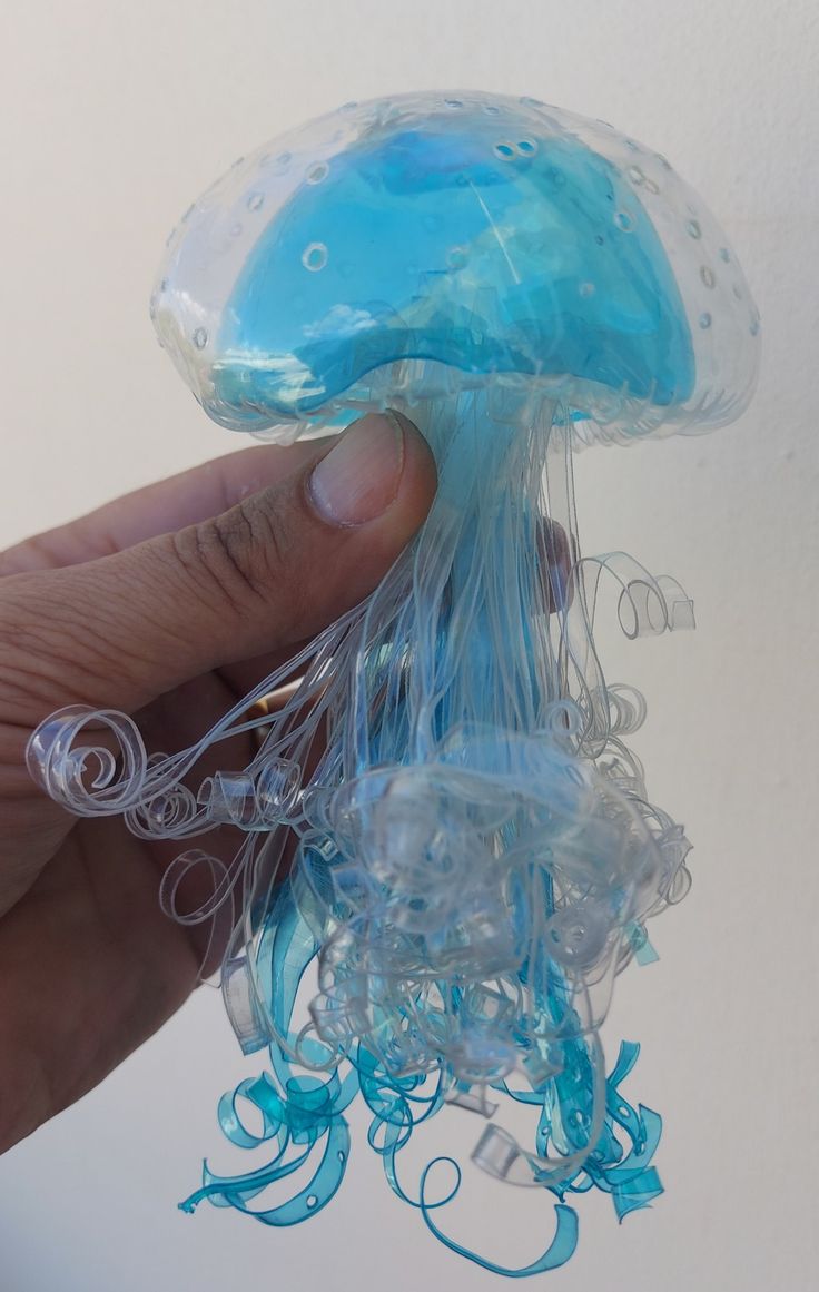 a hand holding a plastic jellyfish toy in it's palm