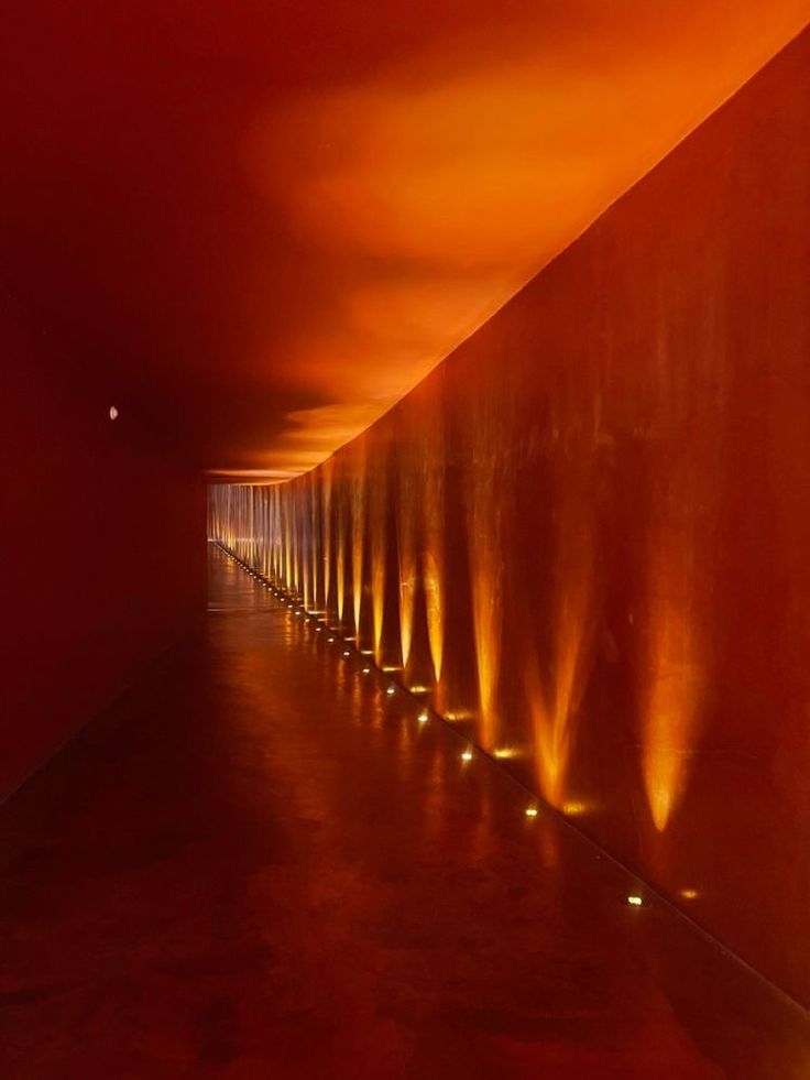 a long row of lights on the side of a wall next to a red wall