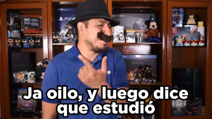 a man with a mustache standing in front of a book shelf