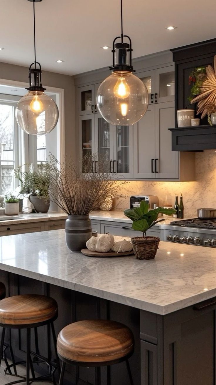 a kitchen island with stools and lights hanging from it's ceiling over the counter