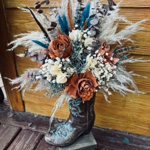 a cowboy boot with flowers and feathers in it sitting on a wooden floor next to a door