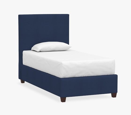 a bed with a blue headboard and white sheets on it's bottom half