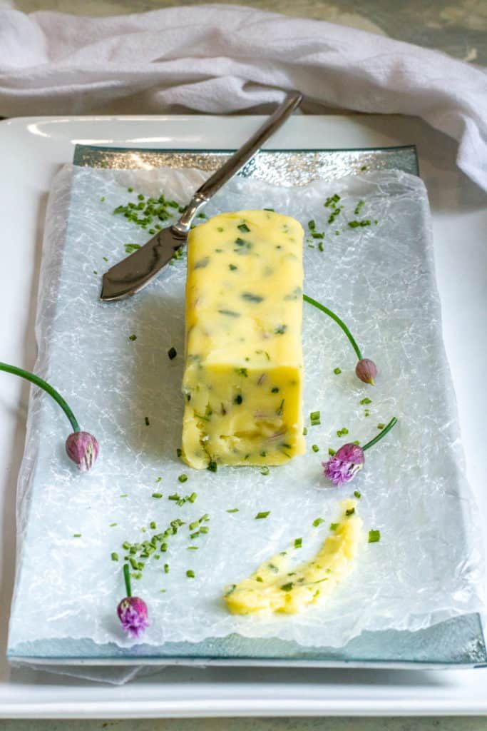 there is a piece of cheese on a plate with flowers and spoons next to it