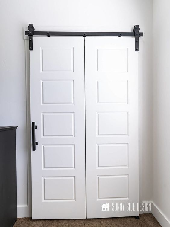 two white doors with black handles in a room