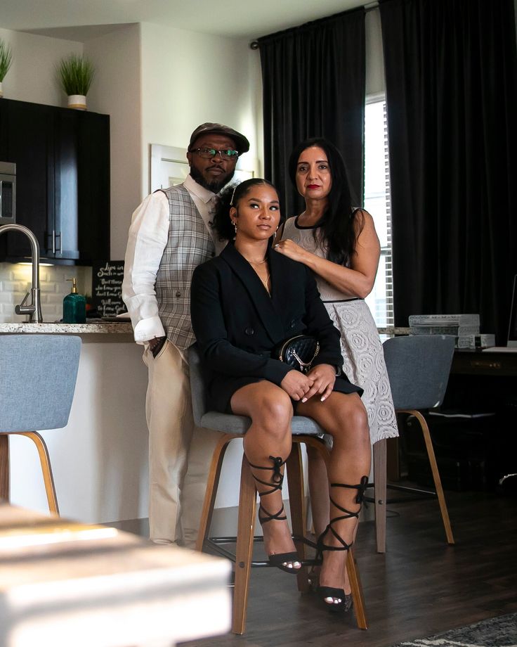 two women and a man are posing for a photo in the kitchen at their home