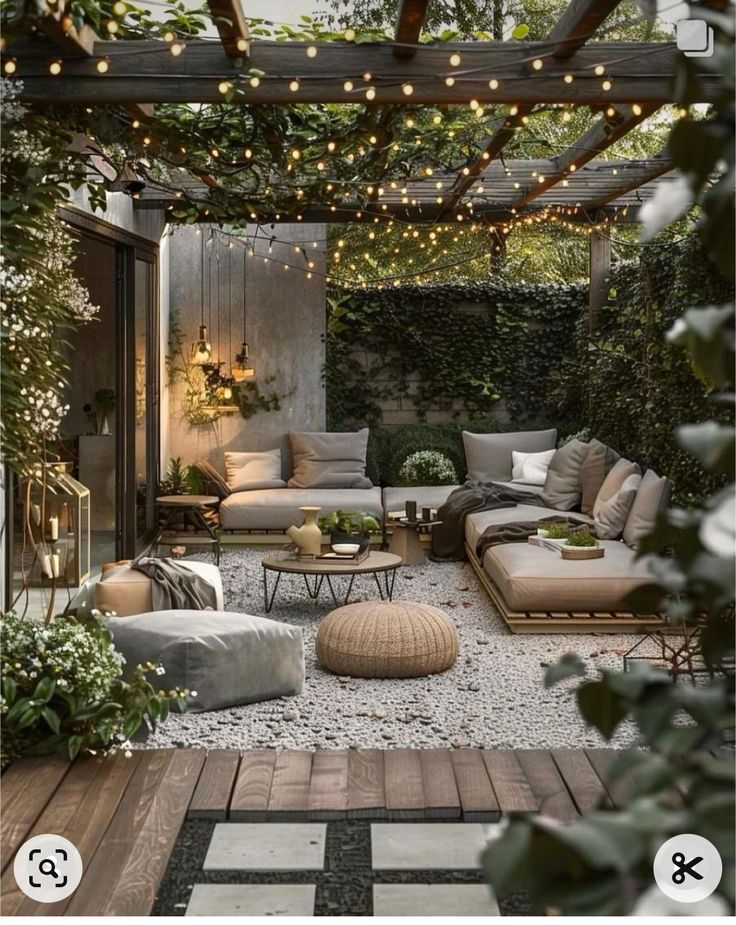 an outdoor living area with couches, tables and lights