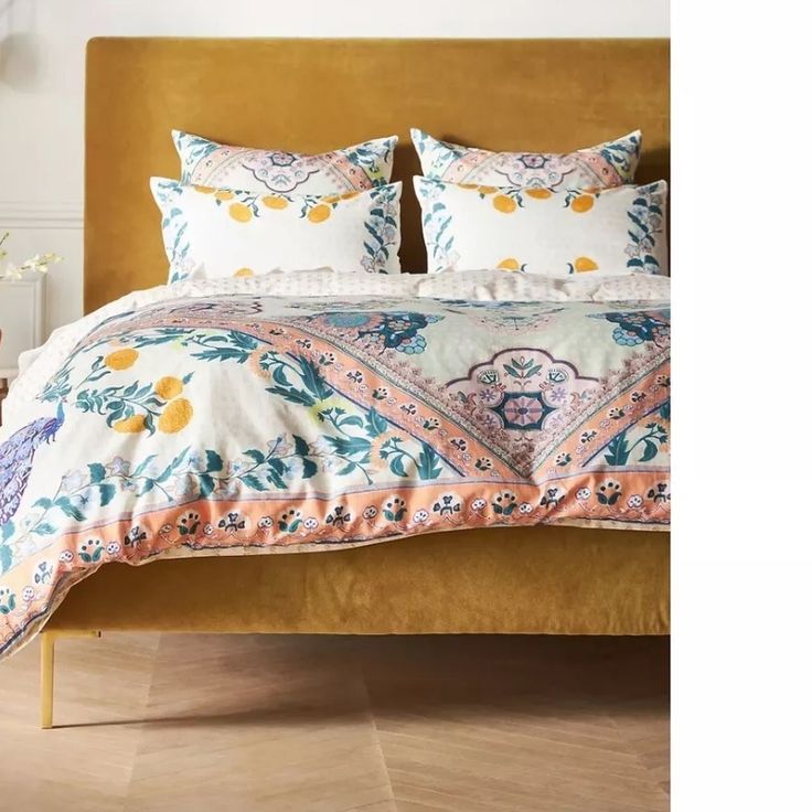 a bed with two pillows on top of it and an orange headboard in the background