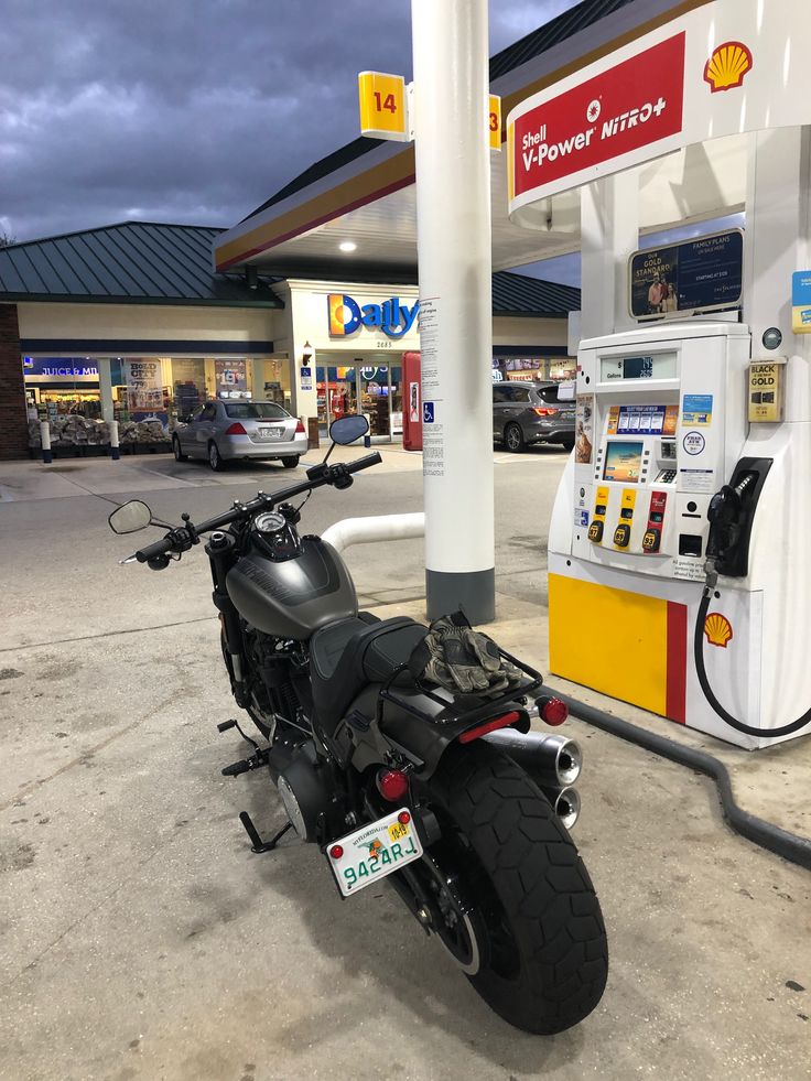 a motorcycle parked in front of a gas station with a shell pump on the side