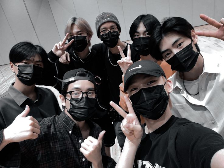 a group of people wearing face masks and giving the peace sign with their hands in front of them