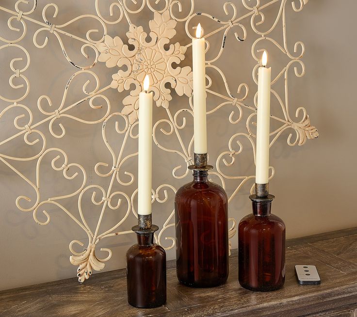 three bottles with candles are sitting on a mantle