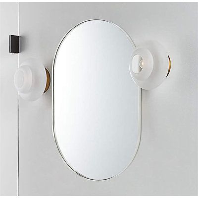 an oval mirror mounted to the side of a white wall next to a light fixture