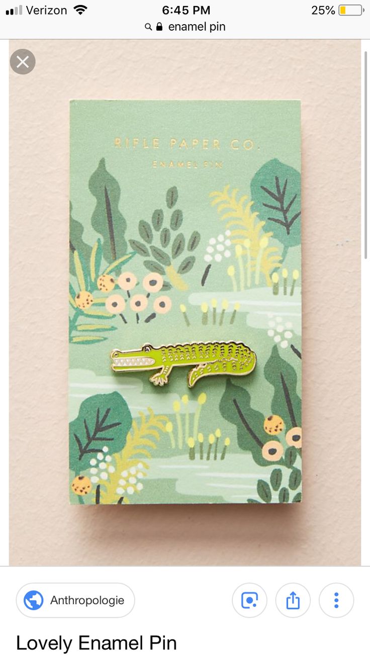 a green and yellow alligator pin sitting on top of a card