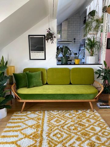 a living room with green couches and potted plants on the floor in front of it