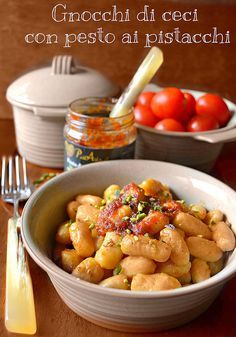 a white bowl filled with pasta next to two bowls of tomatoes and other food items