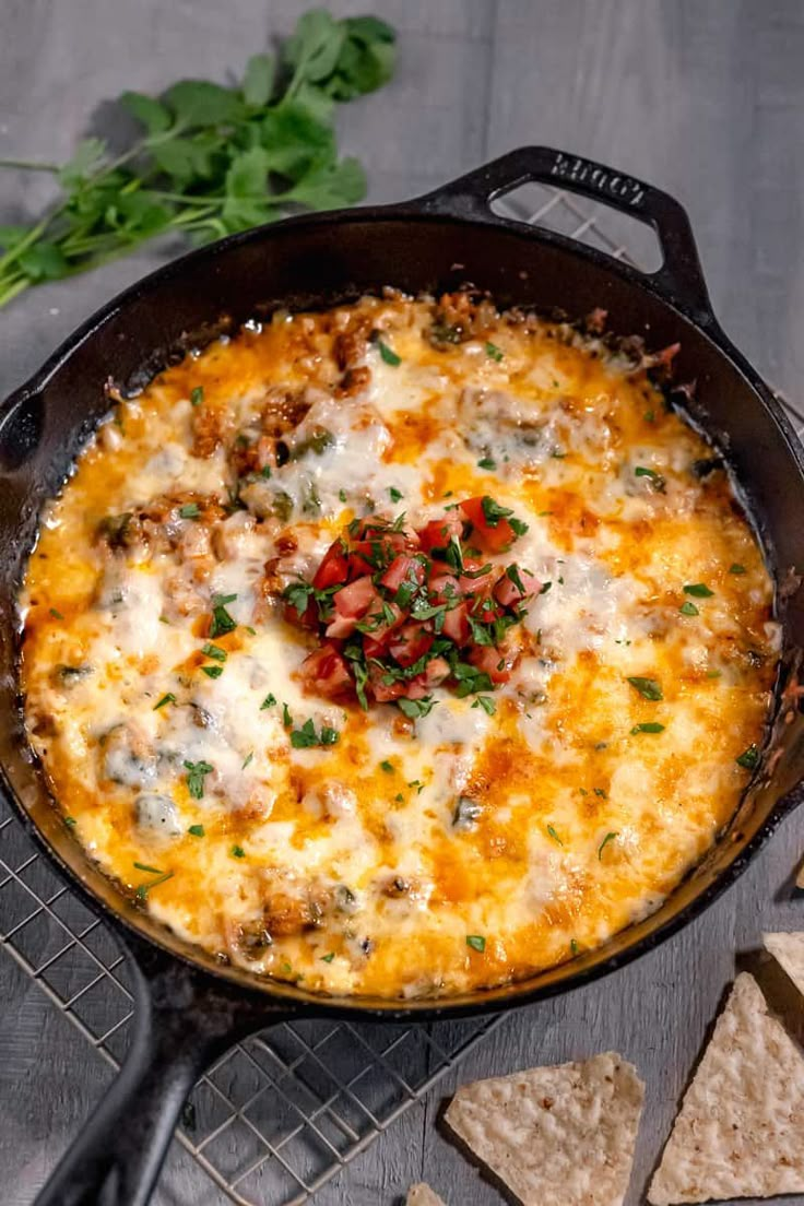 a casserole with cheese, meat and vegetables in a pan next to crackers