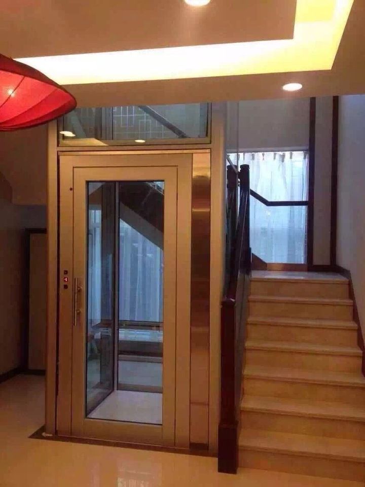 an elevator with glass doors and stairs leading up to the second floor in a building