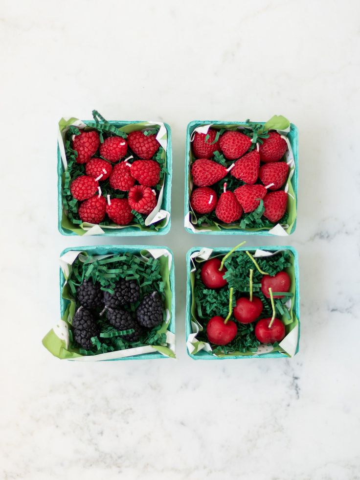 four small trays filled with berries and spinach on top of a white counter