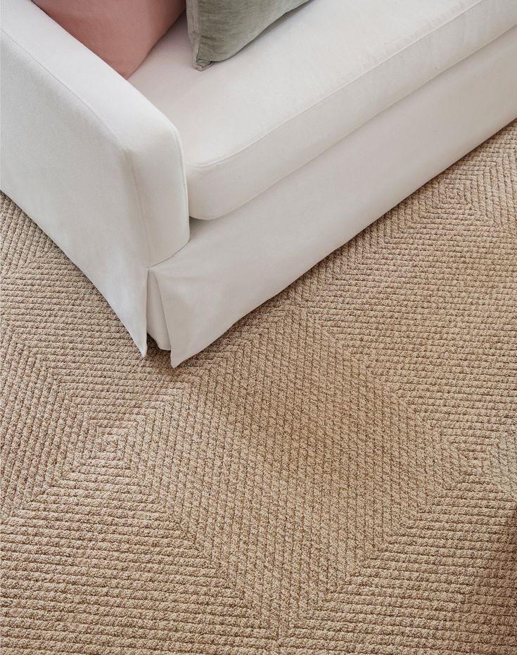 a white couch sitting on top of a carpeted floor next to a pillow and pillows