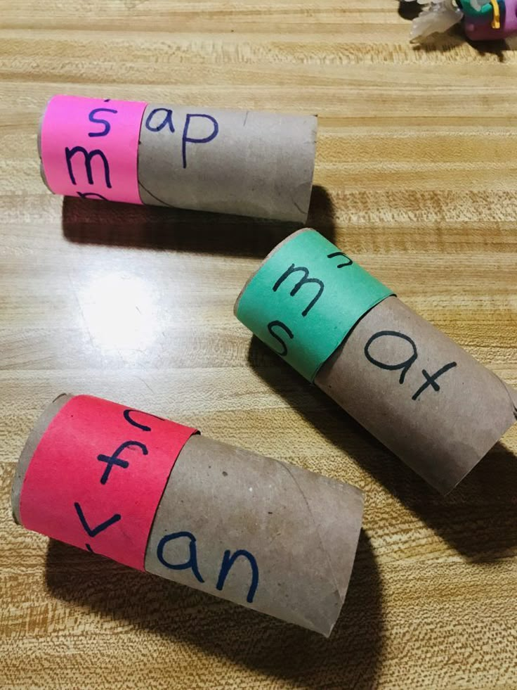 three rolls of toilet paper with words written on them sitting on a wooden table next to pencils