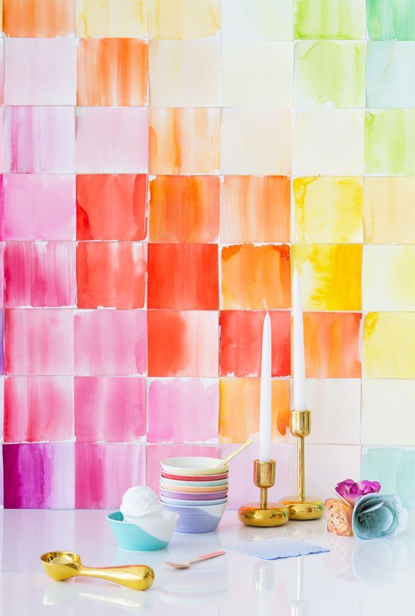 some candles are sitting on a table next to colorful wall tiles and vases with flowers in them