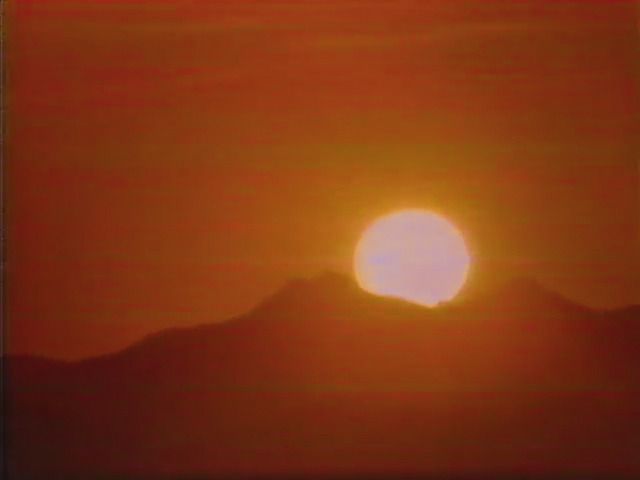 the sun is setting in the sky over mountains