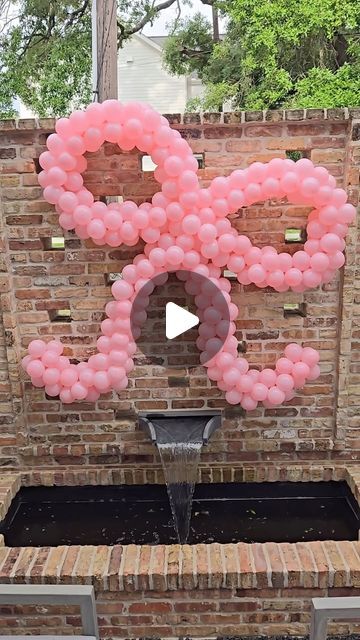 an outdoor fountain with pink balloons floating in the air and a sign that says love