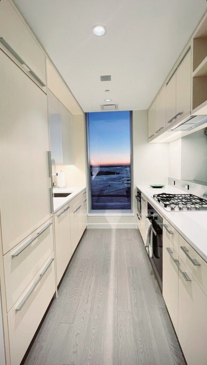 an empty galley kitchen with wood flooring and cabinets