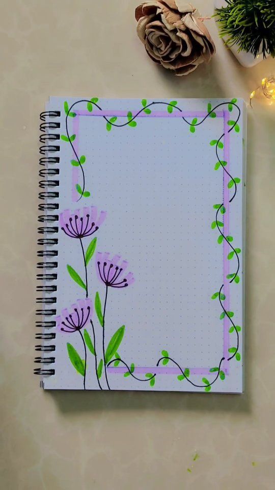 a notebook with flowers painted on it next to a pine cone and some other decorations