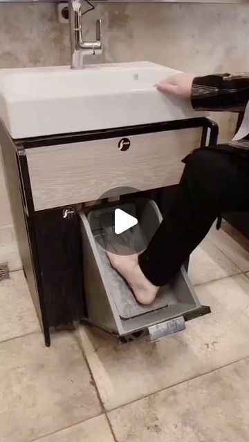 a person sitting on the floor in front of a sink