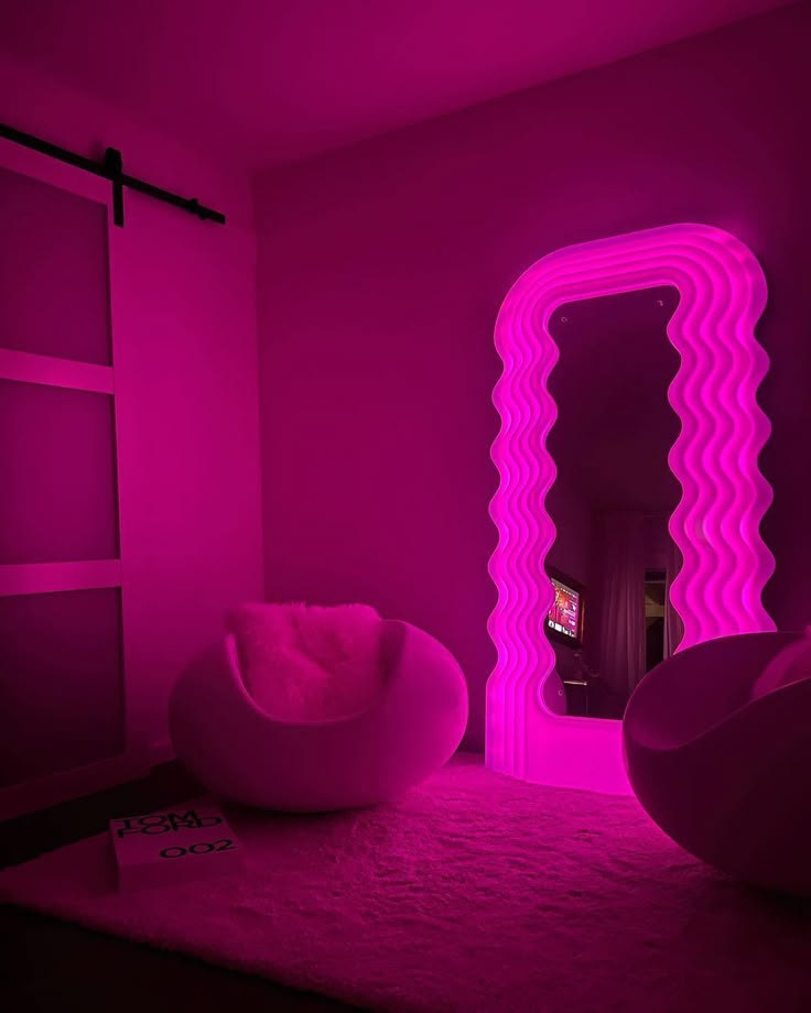 the room is lit up in pink and has a large mirror on the wall above it