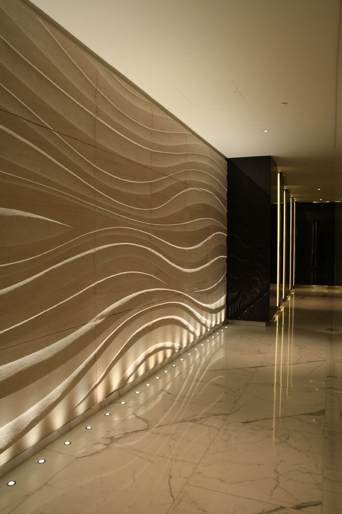 an empty hallway with marble flooring and large wall panels on the walls that have wavy designs