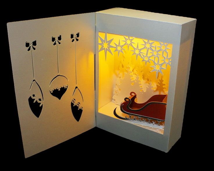 an open card with paper cut out of it and christmas decorations hanging from the front