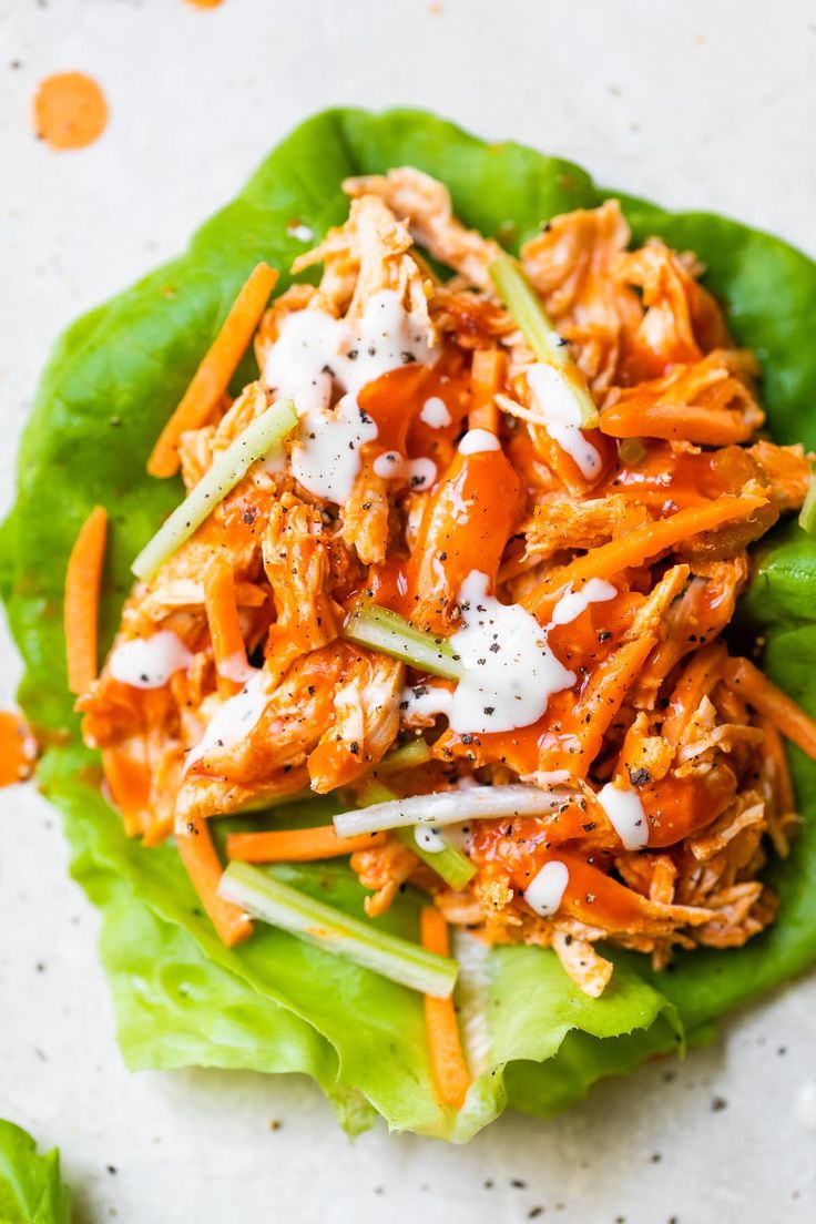 lettuce wraps with shredded meat and dressing on a black plate, ready to be eaten