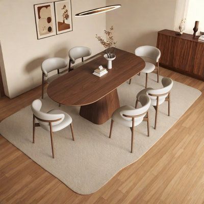 a dining room table with white chairs and a rug on the floor in front of it