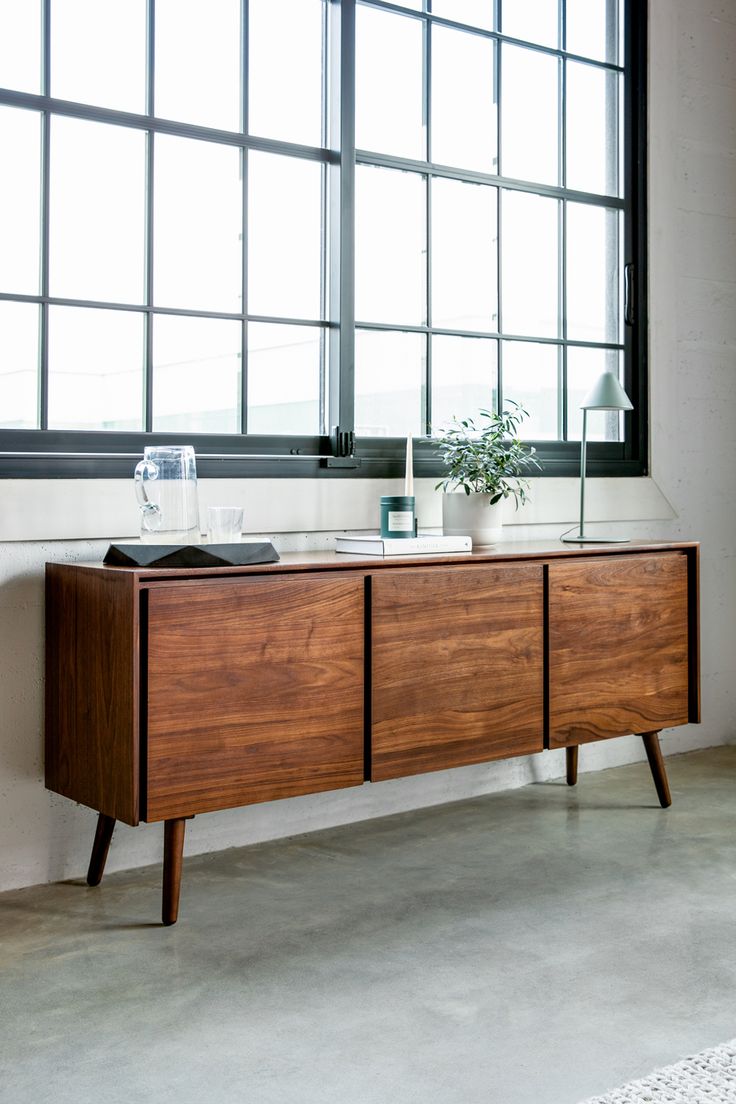 a wooden sideboard sitting in front of a large window