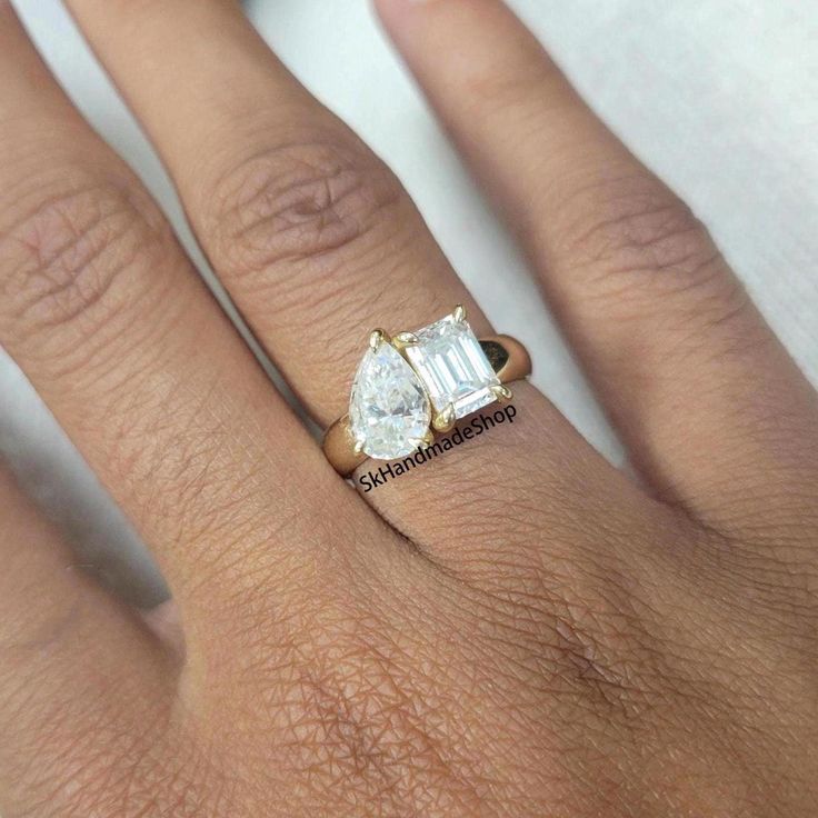 a woman's hand with a diamond ring on top of her finger and an engagement band