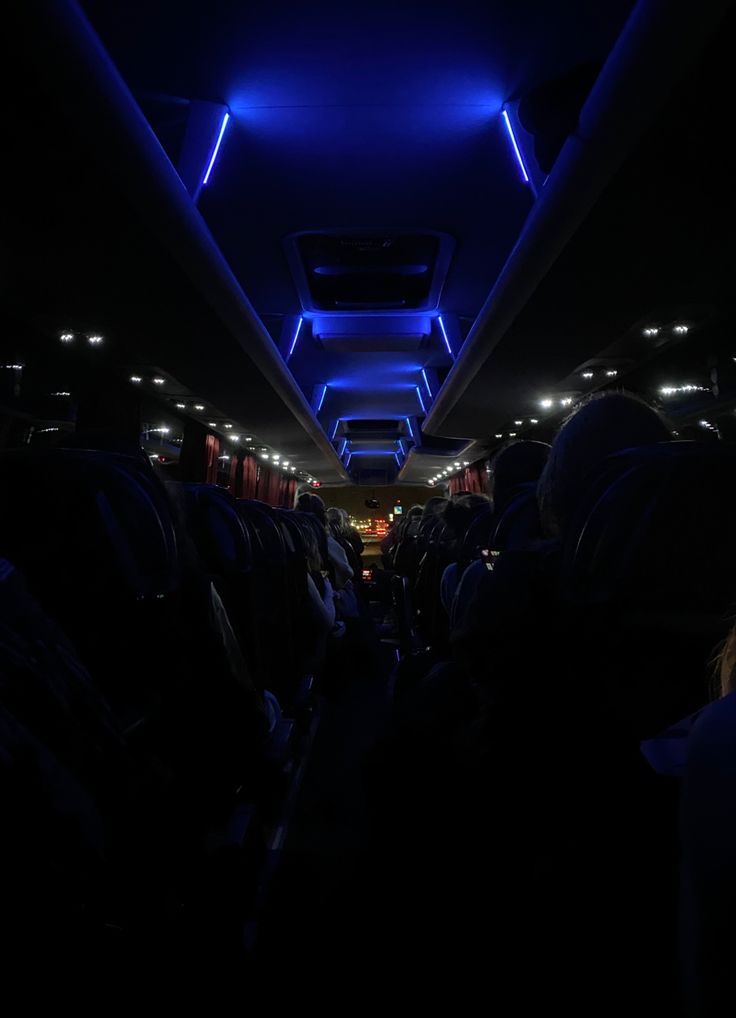 the interior of an airplane with blue lights and people sitting in seats on either side