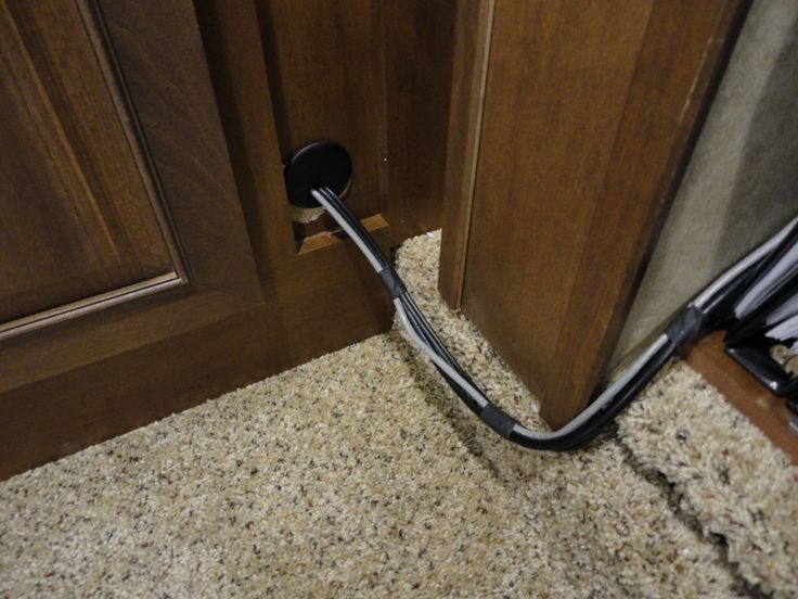 a black hook is in the corner of a kitchen cabinet with carpet on the floor