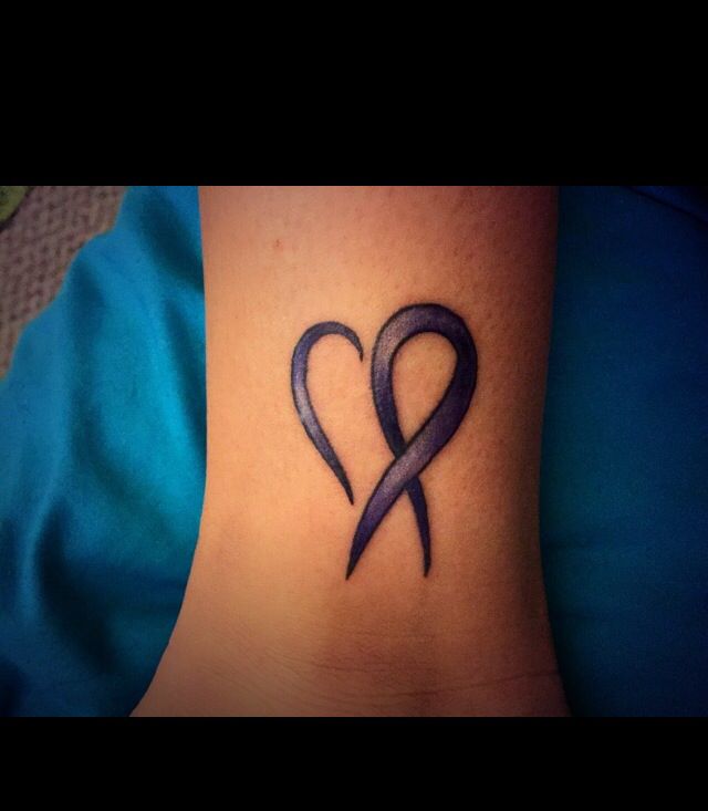 a tattoo on the foot of a woman with a purple ribbon in the shape of a heart