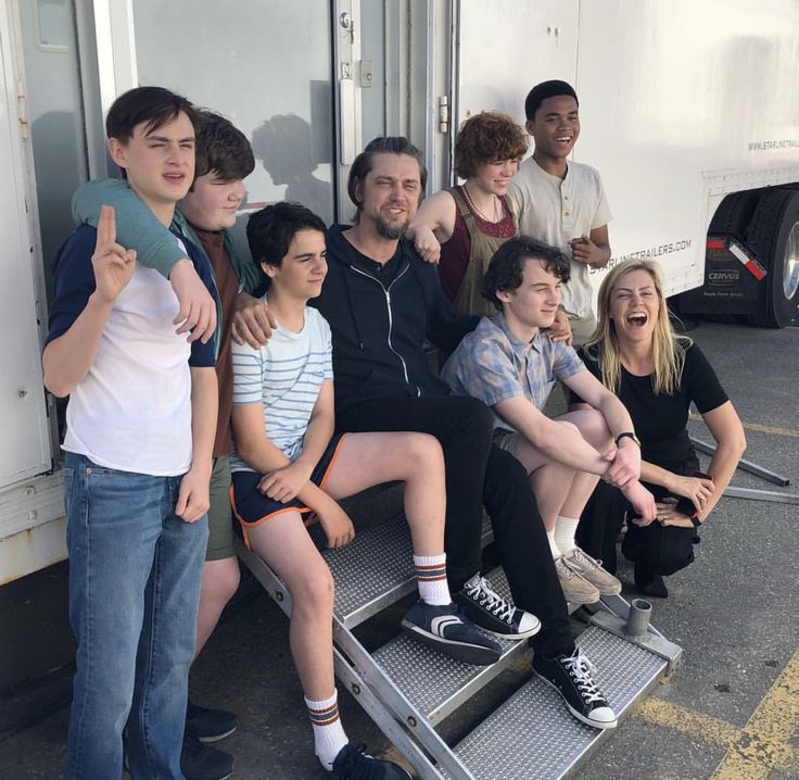 a group of young people sitting on top of a metal bench next to each other