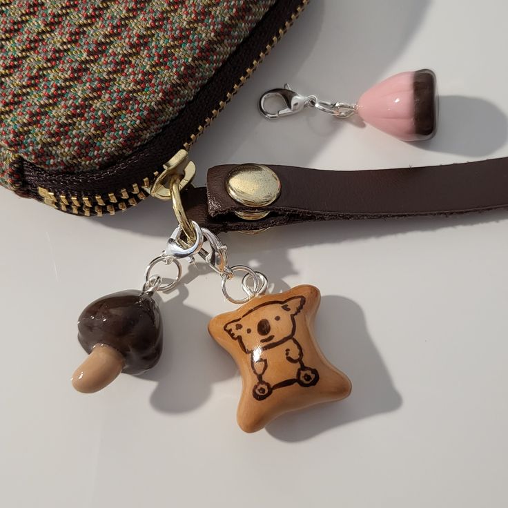 a purse with two charms attached to it sitting on a table next to other items