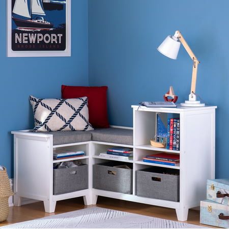 a room with blue walls, white furniture and storage bins on the floor in front of it