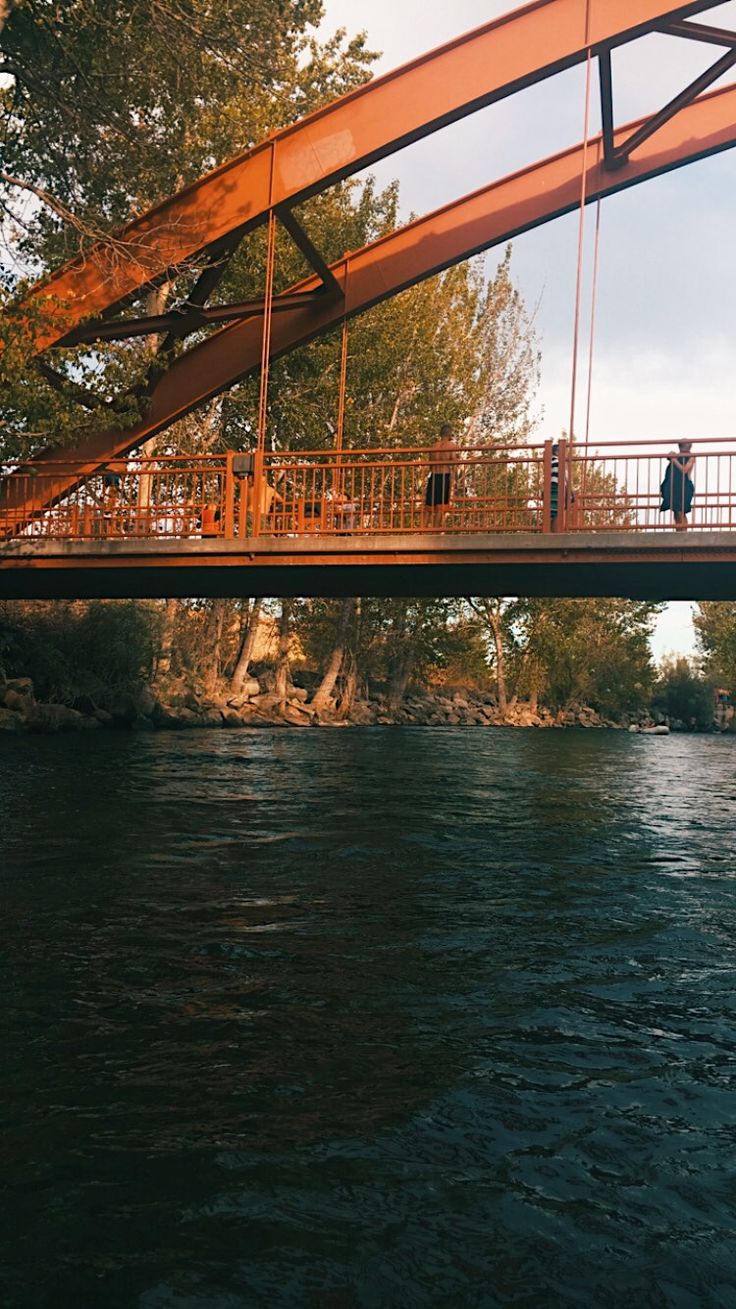 a man walking across a bridge over a river