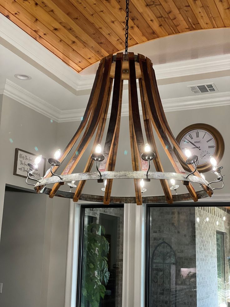 a wooden chandelier hanging from the ceiling in a room with windows and a clock