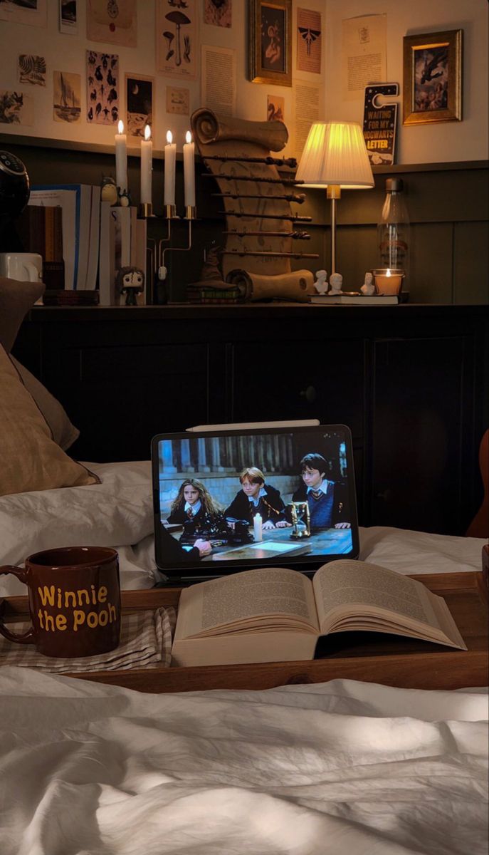 an open book sitting on top of a bed next to a laptop computer and candles