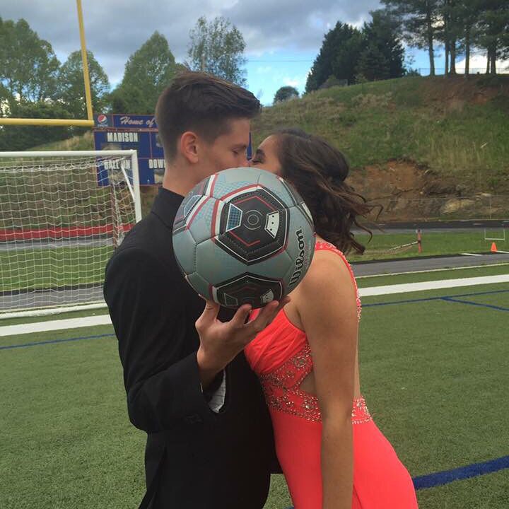 a man and woman kissing while holding a soccer ball