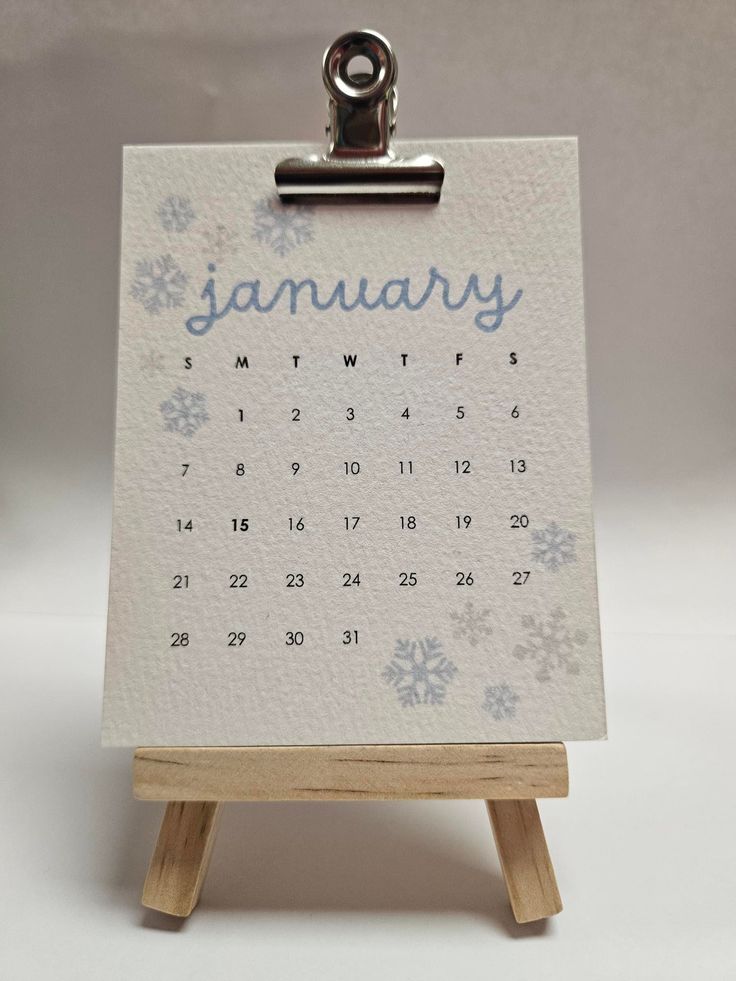 a calendar on a wooden easer with the word january written in blue and white snowflakes