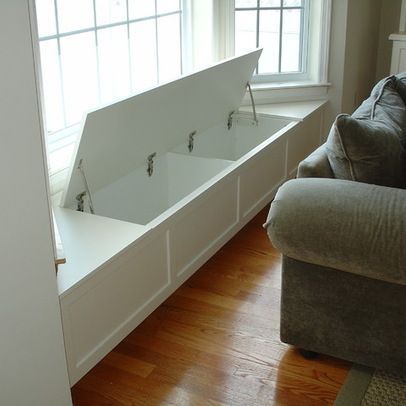 a couch sitting in front of a window next to a white sink on top of a hard wood floor